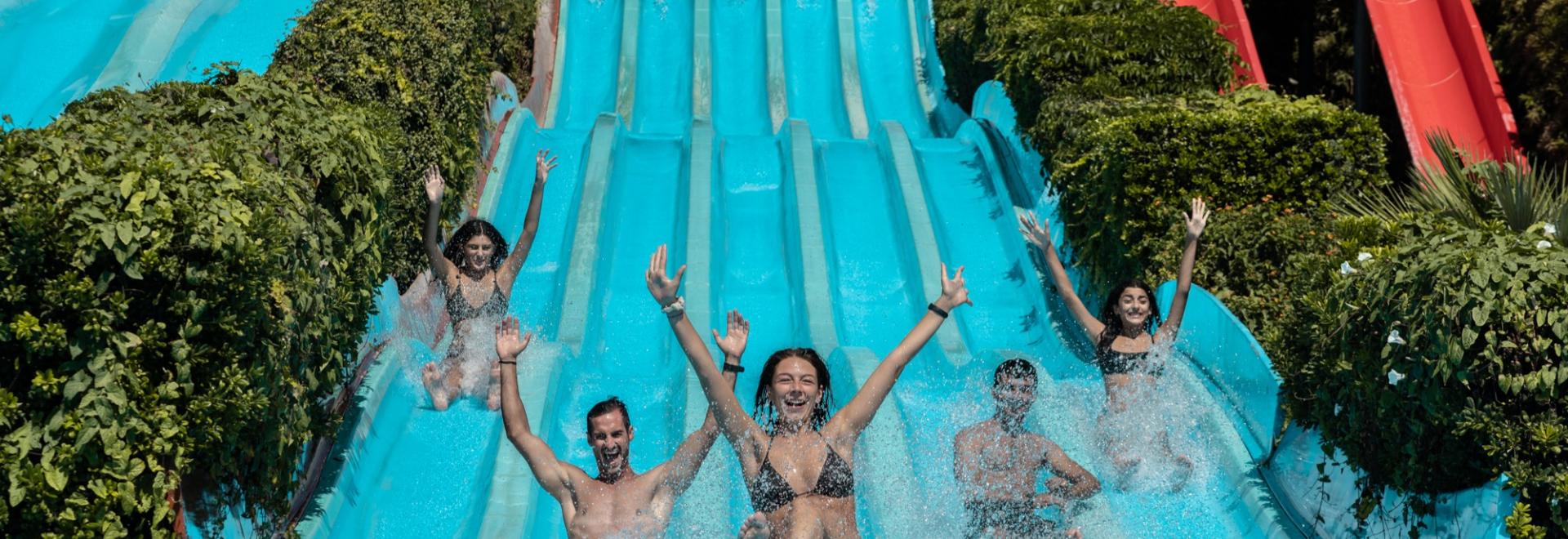 Persone si divertono su scivoli d'acqua in un parco acquatico.